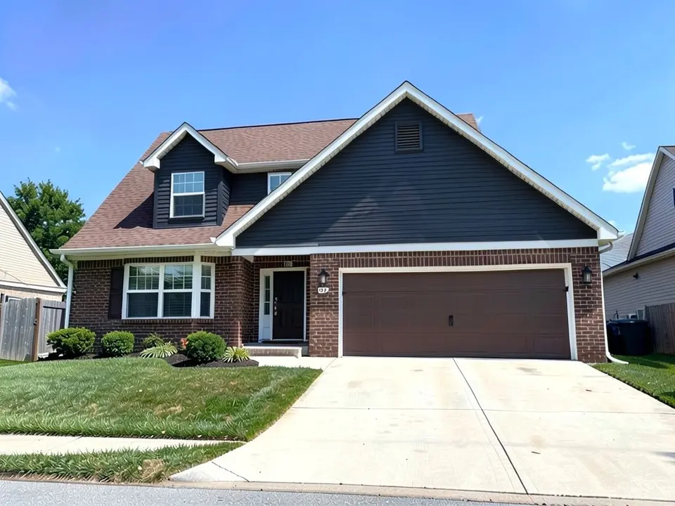 The same house with dark gray siding in the gable and dormer; brown brick, white trim, garage door and brown roof kept
