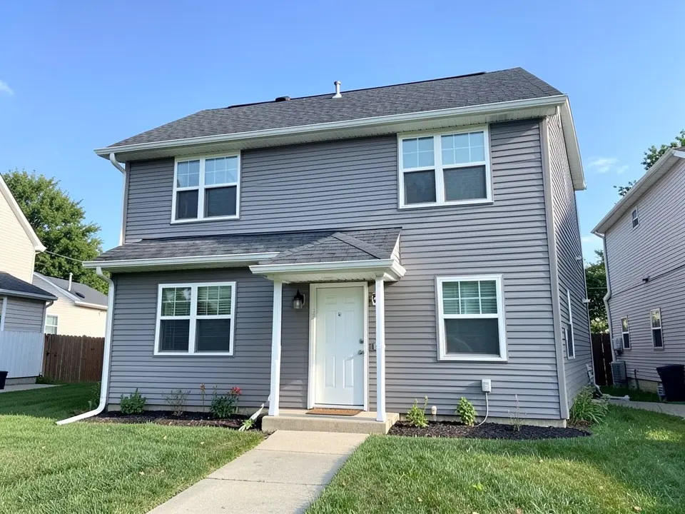 AI-drawn generic stand-in of a gray vinyl-sided two-story house with white trim, a plain white front door under a small porch roof, a dark gray roof and a green lawn