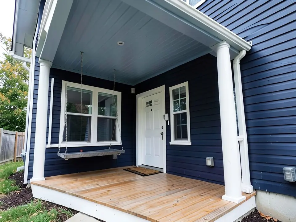 The same porch with a muted gray-blue ceiling; navy walls, white trim and posts, wood floor, door and swing kept