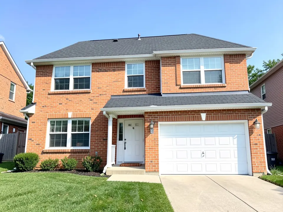 AI-drawn generic stand-in of a two-story house with red-orange brick walls, white window trim, a white front door, a white garage door and a dark gray shingle roof