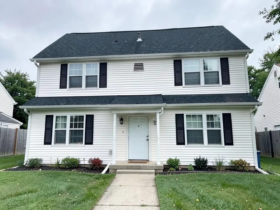 The same house with a very dark charcoal roof on the main roof and the entry roof; white siding, black shutters, door and walkway kept