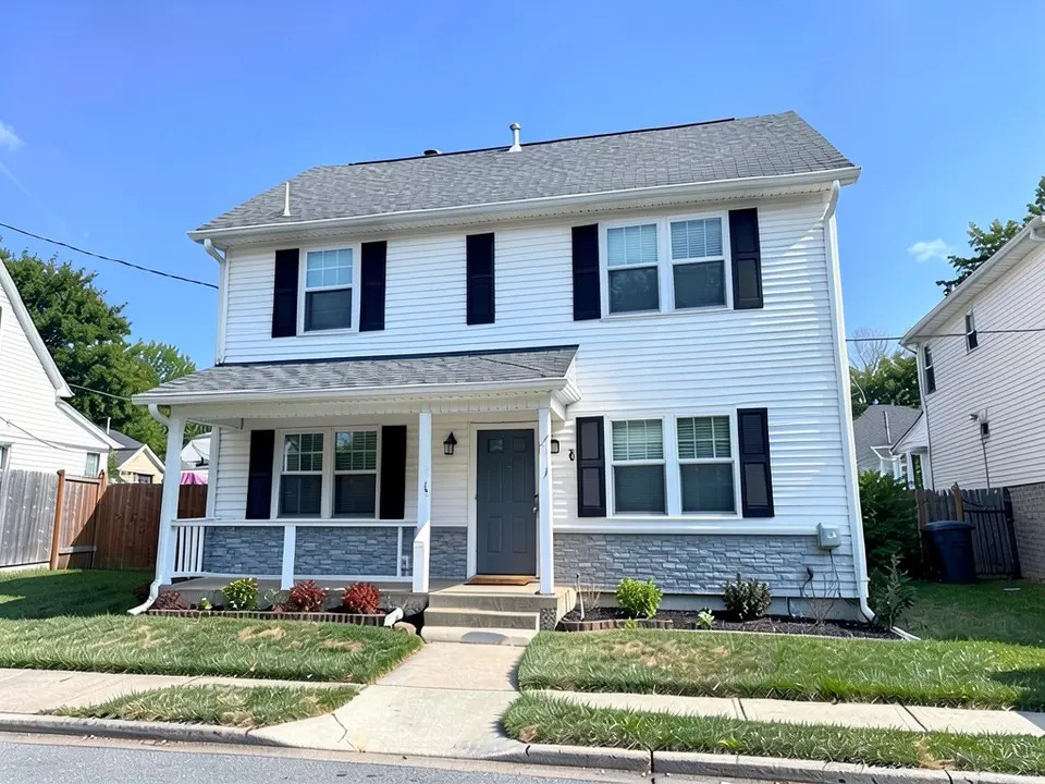 The same house with gray ledgestone along the bottom of the front walls; white siding above, shutters, door and roof kept