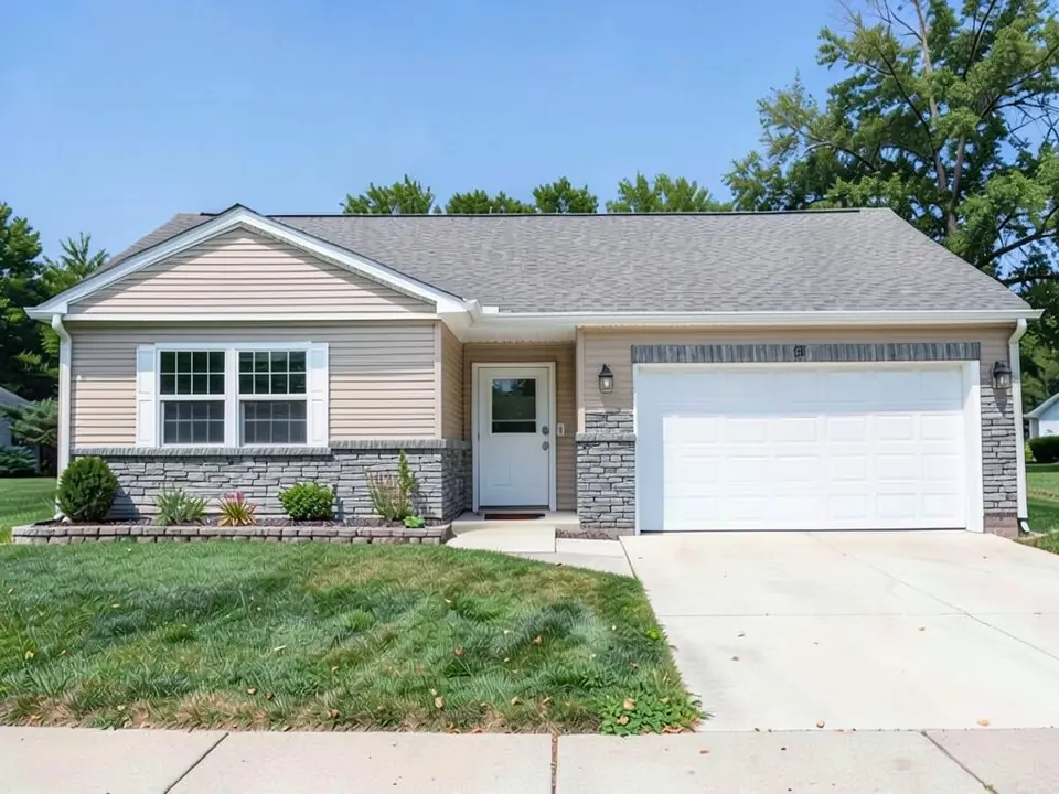 The same ranch house with a gray stacked stone wainscot under the front windows and gray stacked stone on both sides of the garage door