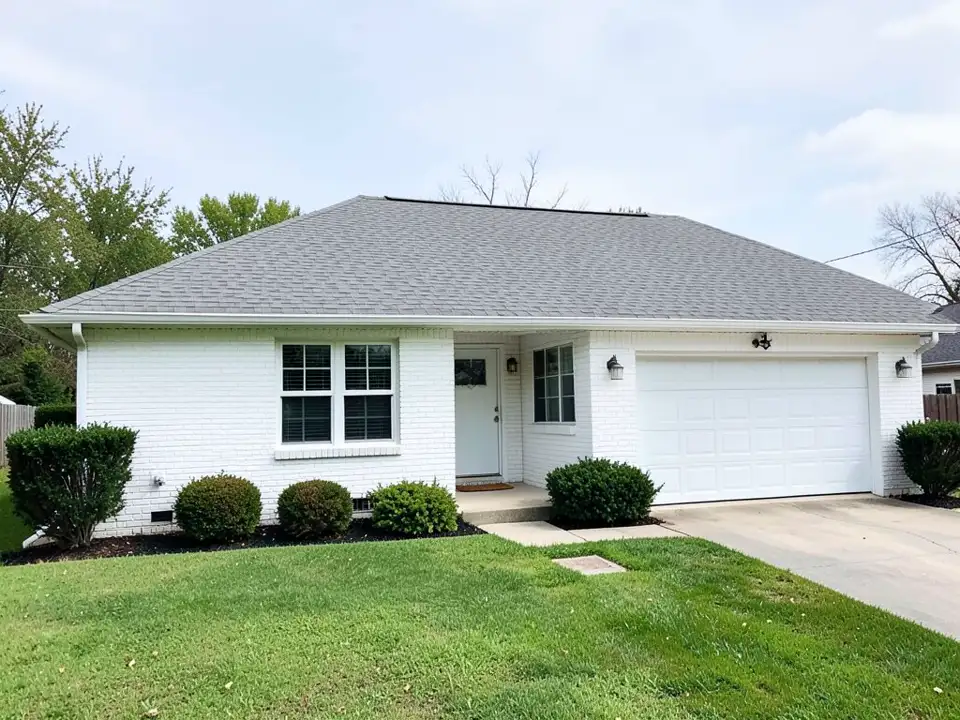 AI-drawn generic stand-in of a one-story ranch house with white painted brick, white window trim, a white garage door, a grey shingle roof, a concrete driveway, shrubs and a lawn